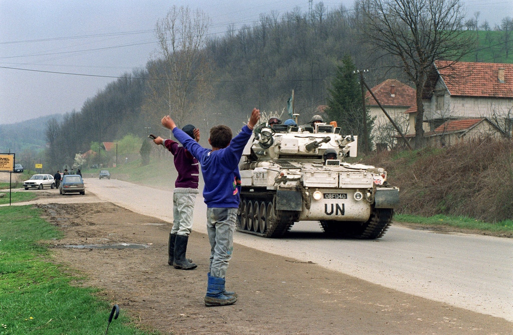 Two Bosnian boys salute a Canadian blue helmets convoy, 17 April 1993 near Tuzla, departing for the Moslem enclave of Srebrenica, where some 30000 refugees hope to be evacuated from.