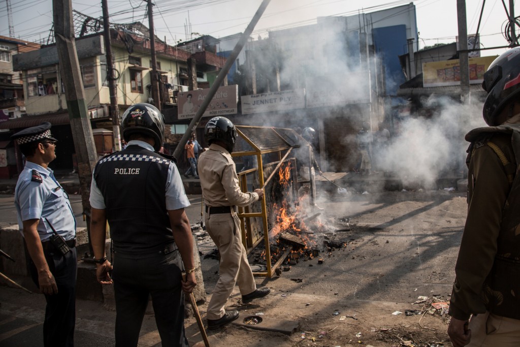 Police officials remove burning barricade on a street in Guwahati, Assam, Dec. 12, 2019.