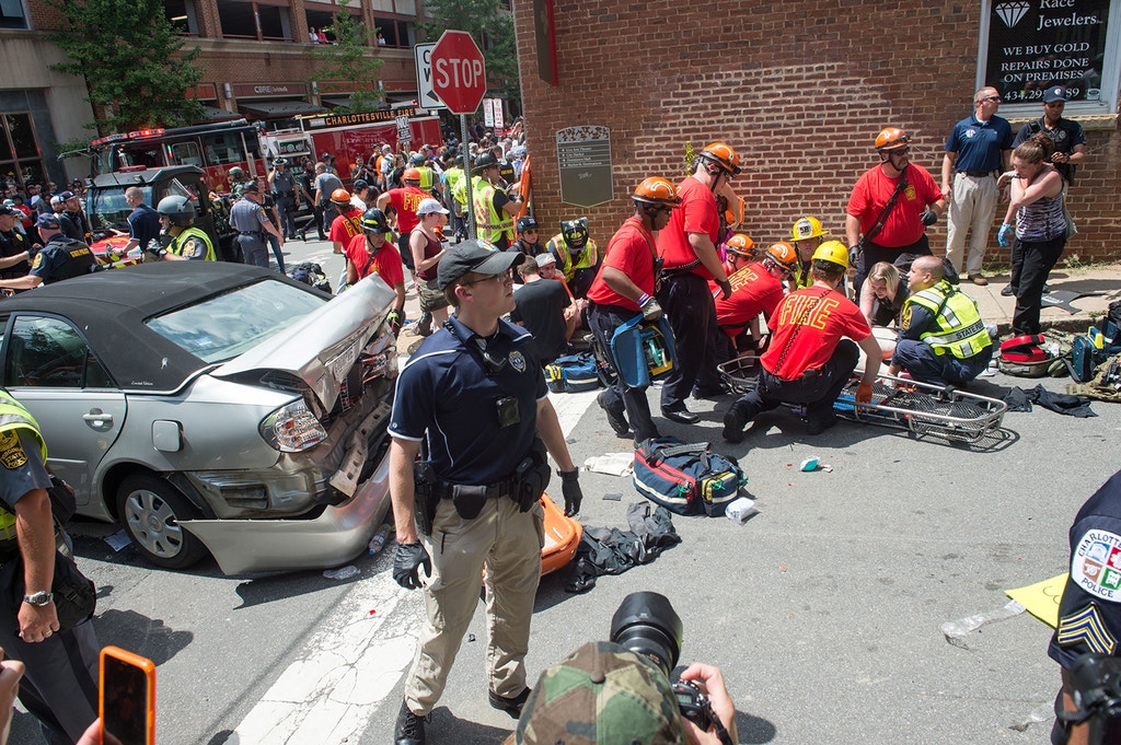 TOPSHOT - A woman is received first-aid after a car accident ran into a crowd of protesters in Charlottesville, VA on August 12, 2017. - A picturesque Virginia city braced Saturday for a flood of white nationalist demonstrators as well as counter-protesters, declaring a local emergency as law enforcement attempted to quell early violent clashes. (Photo by Paul J. RICHARDS / AFP) (Photo credit should read PAUL J. RICHARDS/AFP via Getty Images)