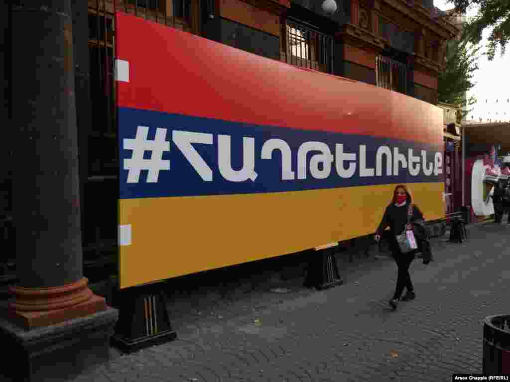 A woman walks past a large Armenian flag with the hashtag &quot;we will win&quot; on October 28.&nbsp;