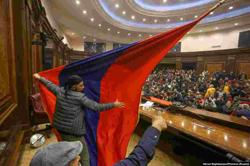 Protesters put up an Armenian flag inside of parliament. Objects were thrown, chairs smashed, and scuffles broke out at the podium.&nbsp;