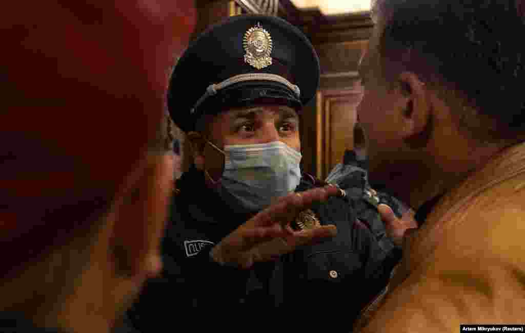 A policeman speaks with protesters inside Armenia's parliament building.&nbsp;