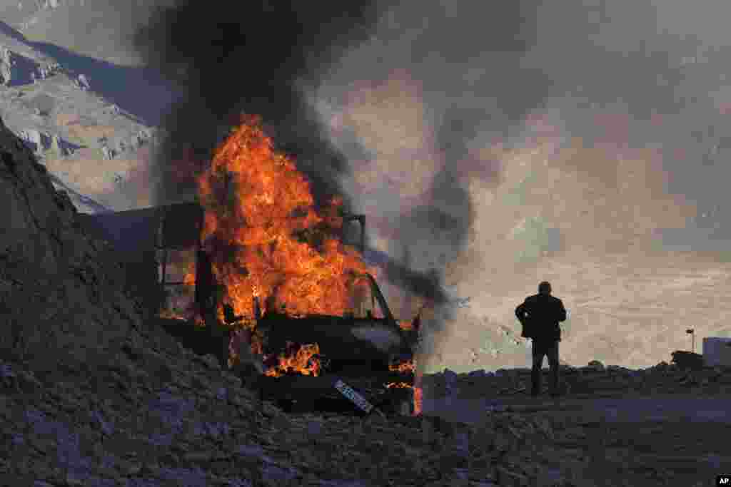 A man stands near a burning car on a mountain road between Nagorno-Karabakh and Armenia as heavy fighting continued around the town of Shushi/Susa on November 8.