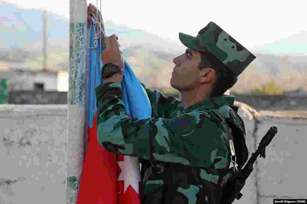 An Azerbaijani soldier hoists his country's flag during a ceremony in the village of Mincivan, which was recently taken from Armenian forces.&nbsp;