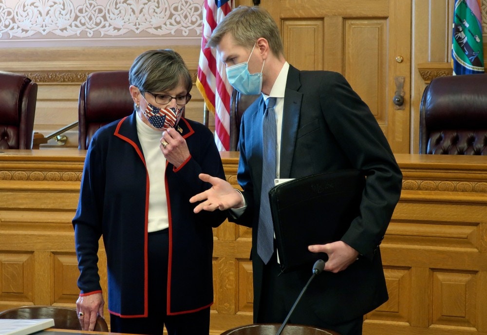 Kansas Gov. Laura Kelly, left, confers with Clay Britton, her chief attorney, before a meeting with legislative leaders about an executive order she issued to require people to wear masks in public, Thursday, July 2, 2020, at the Statehouse in Topeka, Kan. Kelly says she's worried that if the state doesn't reverse a recent surge in reported coronavirus cases, the state won't be able to reopen K-12 schools in August. (AP Photo/John Hanna)