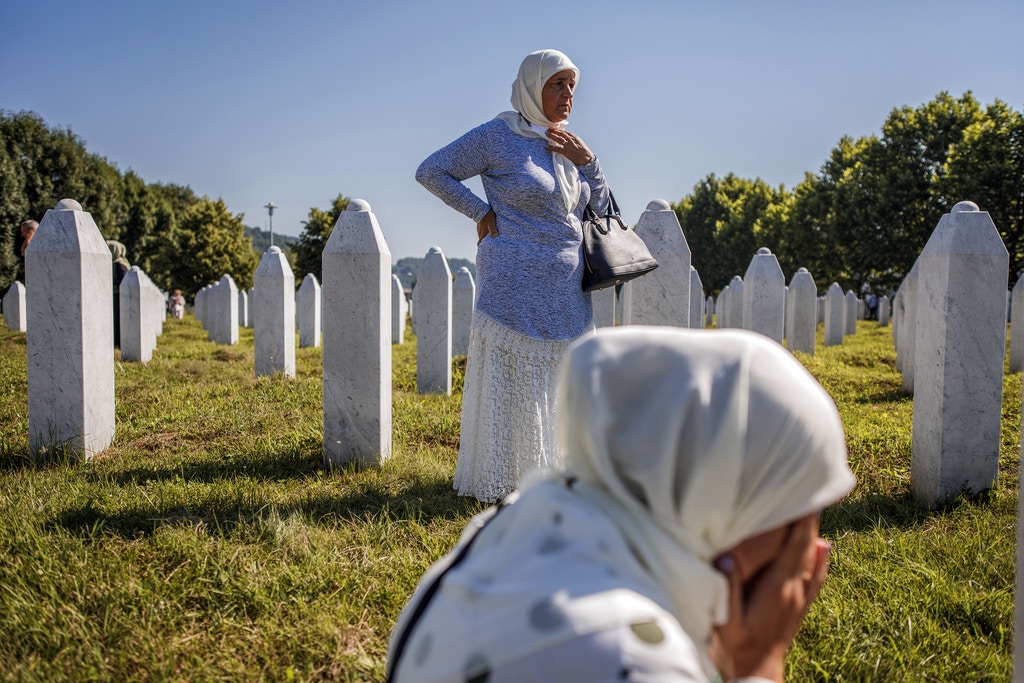 SREBRENICA, BOSNIA AND HERCEGOVINA - JULY 11: A Bosnian Muslim woman and her mother mourn by a grave of their father and husband on July 11, 2020 as newly identified victims are buried at the cemetery for victims of Srebrenica genocide in Potocari near Srebrenica, Bosnia and Hercegovina. More than 8,000 Bosnian Muslim men and boys were killed after the Bosnian Serb Army attacked Srebrenica, a designated UN safe area, on 10-11 July 1995, despite the presence of UN peacekeepers. There have been high-level prosecutions of some principal architects of the war in Bosnia and Herzegovina, including Ratko Mladic and Radovan Karadzic, yet there is still a backlog of cases pending before courts in the country. (Photo by Damir Sagolj/Getty Images)