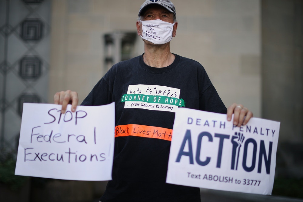 WASHINGTON, DC - JULY 13: Anti-death penalty activists Art Laffin of Journey of Hope and demonstrates in front of the U.S. Justice Department's Robert F. Kennedy Building July 13, 2020 in Washington, DC. A U.S. District Court judge issued an injunction hours before the scheduled execution by lethal injection of Daniel Lee, 47, at the U.S. Penitentiary in Terre Haute, Indiana. It would have been the first federal execution in 17 years. Lee was sentenced to die for the brutal 1996 murder of a family of three in Arkansas as part of a robbery aimed at raising funds for a white supremacist organization. (Photo by Chip Somodevilla/Getty Images)
