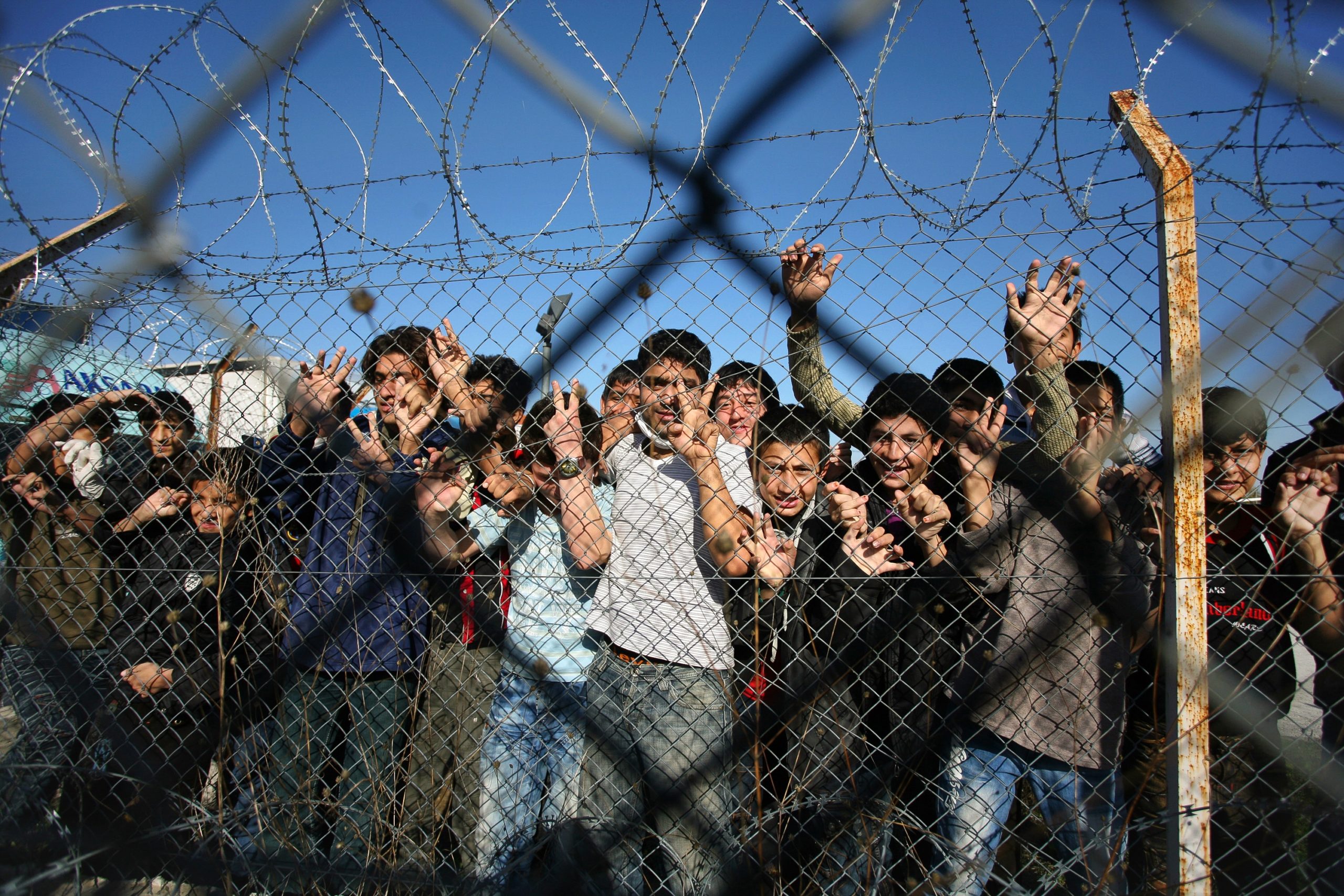 Immigrant minors peer out through the fence of an immigrant detention center in the village of Filakio, on the Greek-Turkish border, upon the arrival there of the Frontex Rapid Border Intervention Teams (RABITs) and EU officials on November 5, 2010. Border guards from 26 nations began arriving on November 2 in northeastern Greece to help curb a wave of illegal immigrants crossing over from Turkey, European border agency Frontex said. Coordinated by Greek police, some 170 guards will be on hand and until the end of December to monitor borders and scout for illegal immigrants, Frontex spokesman Michal Parzyszek said. AFP PHOTO /Sakis Mitrolidis (Photo credit should read SAKIS MITROLIDIS/AFP via Getty Images)