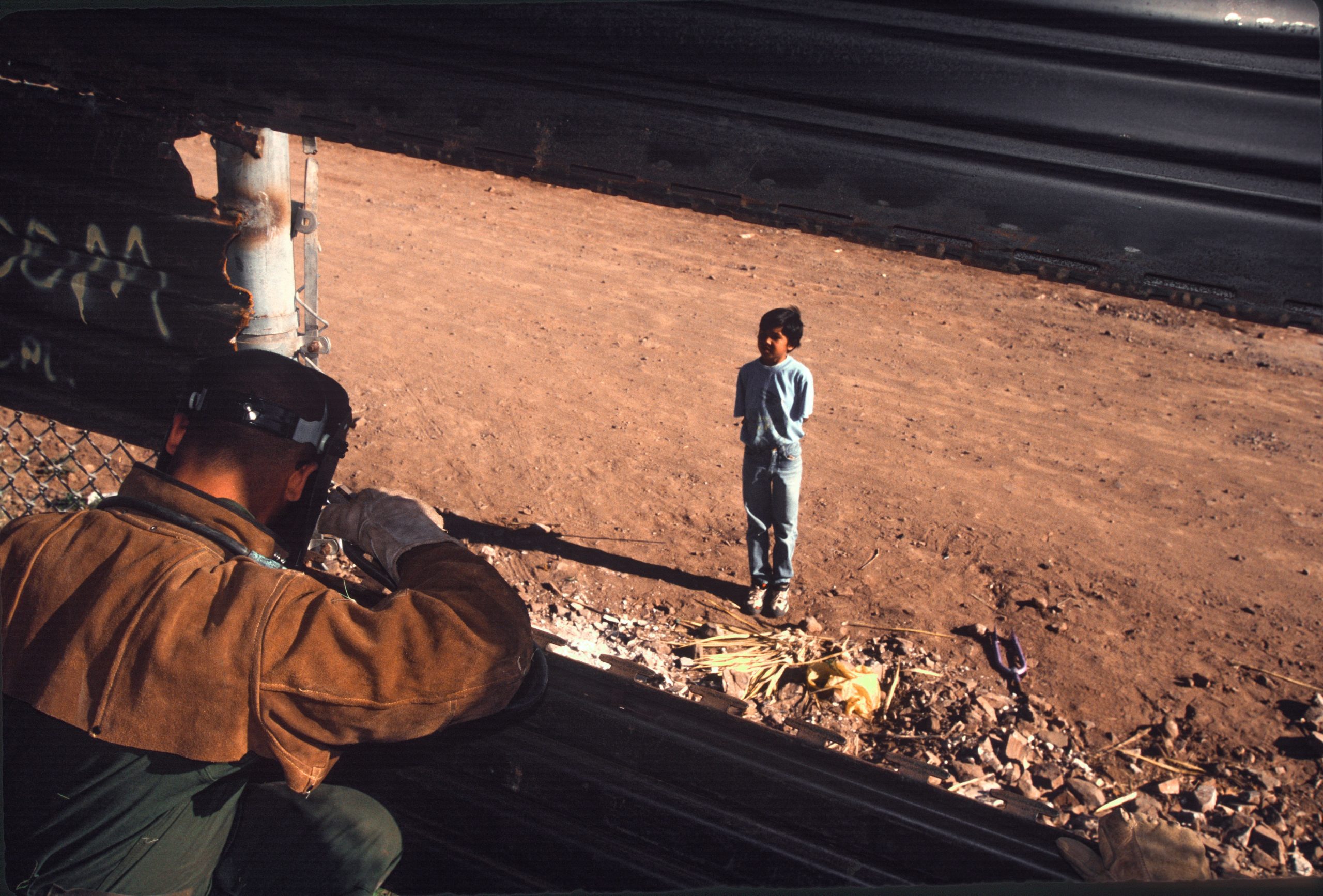 NOGALES, AZ - APRIL 10: United States army engineers extend a border wall as a Mexican boy on the other side watches on April 10, 1995 on the outskirts of Nogales, Arizona.(Photo by Andrew Lichtenstein/Corbis via Getty Images)