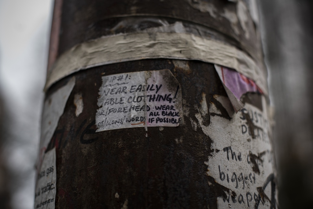 An electric post covered in stickers, including a tip for protesters to "wear all black" is seen near Chapman Square, in downtown Portland, Oregon, on January 30, 2021. The square is a common site for protests, due to its proximity to the Multnomah County Justice Center and the Mark O. Hatfield Federal Courthouse.