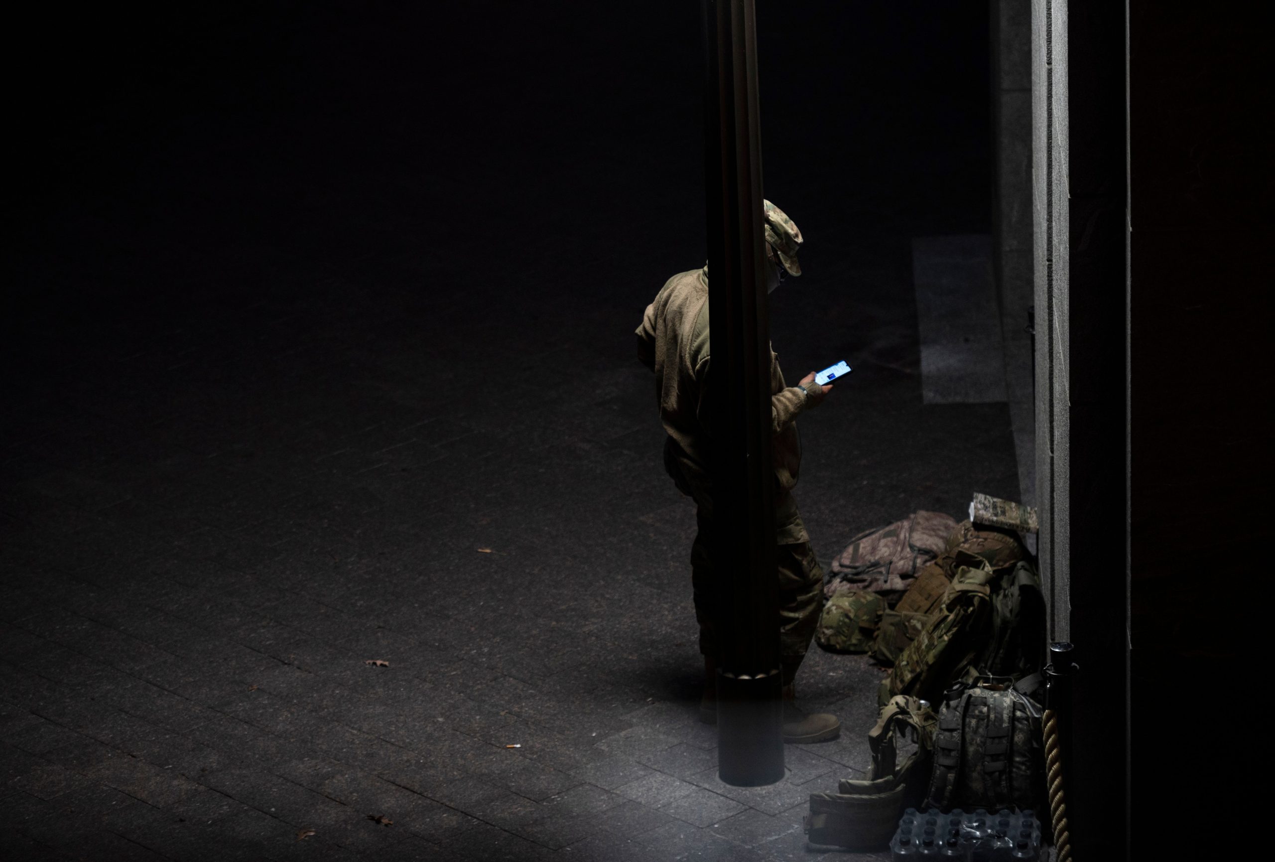 A member of the US National Guard looks at his phone as he takes a break at the US Capitol in Washington, DC on January 17, 2021, during a nationwide protest called by anti-government and far-right groups supporting US President Donald Trump and his claim of electoral fraud in the presidential election.