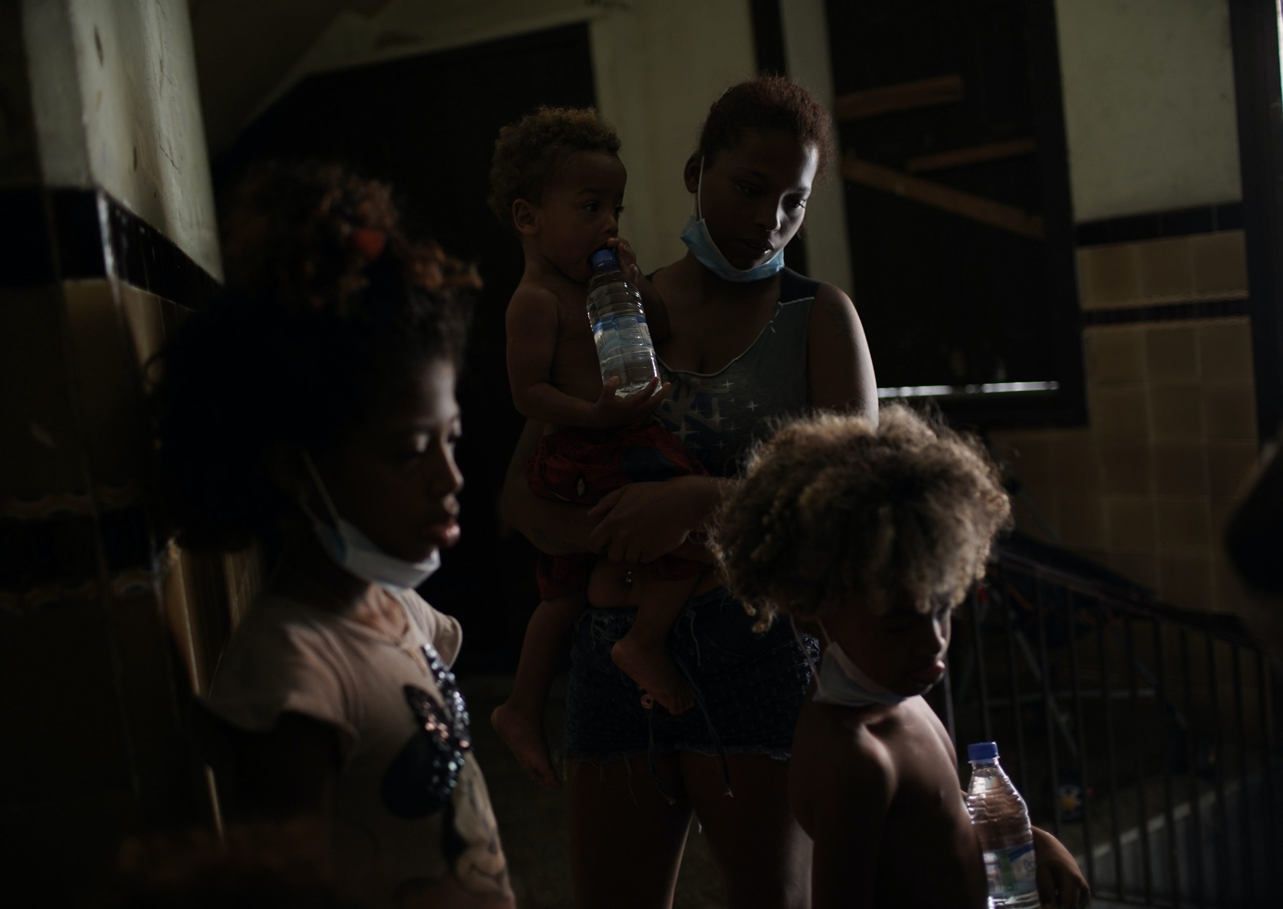 Residents wait to be served a plate of food donated by aid groups, inside an occupied building amid the new coronavirus pandemic, in Rio de Janeiro, Brazil, on March 10, 2021.